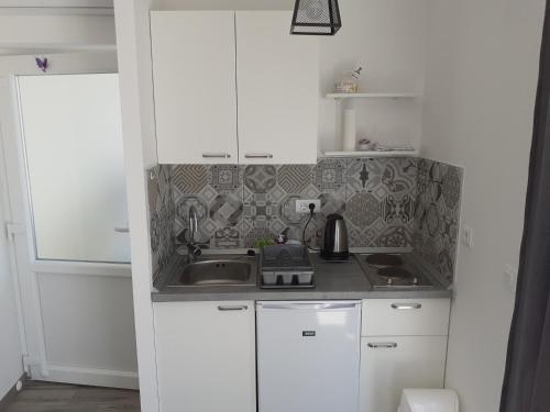 una pequeña cocina con armarios blancos y fregadero en Studio Ela, en Baška Voda