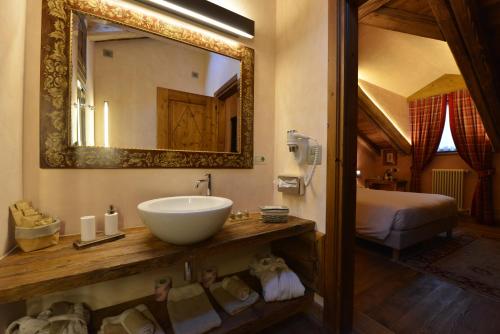 a bathroom with a sink and a mirror and a bed at Le Reve Charmant in Aosta