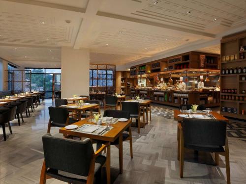 a restaurant with wooden tables and chairs and a bar at Novotel Chennai Chamiers Road in Chennai
