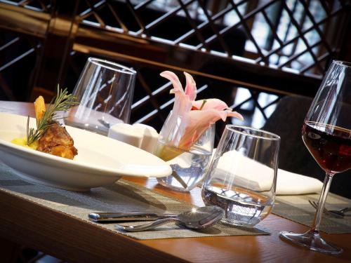 a table with a plate of food and glasses of wine at Novotel Chennai Chamiers Road in Chennai