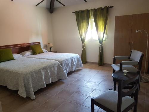 a bedroom with two beds and a chair and a window at El Mirador del Abuelo in Cabeza del Buey