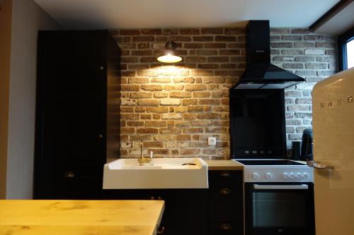 a kitchen with a sink and a brick wall at Gîtes le second à Spa (gîte de 2 et de 5 personnes) in Spa
