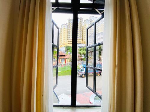 a window with yellow curtains looking out at a street at Hotel Rainbow in Cameron Highlands