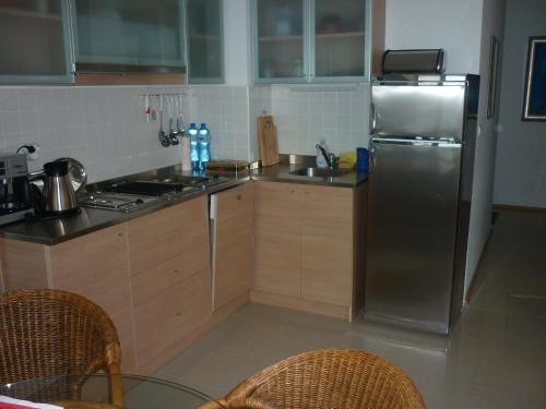 a kitchen with a stainless steel refrigerator and wooden cabinets at Апартмент Blue Sky in Sveti Vlas