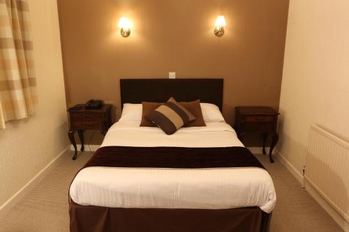 A bed or beds in a room at The Cedars Hotel, Loughborough 
