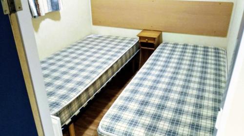 - 2 lits dans une petite chambre avec des draps en damier dans l'établissement Camping baradis, à Commensacq