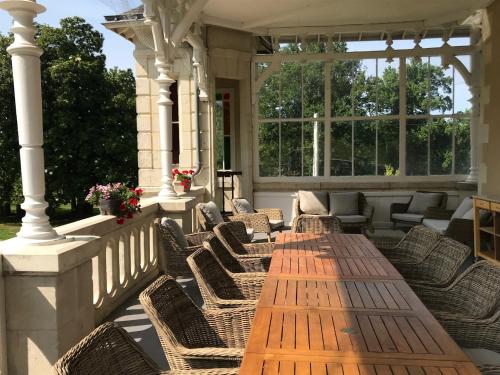 un patio con sedie e un tavolo di legno su un portico di Chateau Vary a Jarzé
