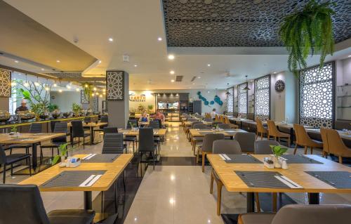 ein Restaurant mit Holztischen und -stühlen und Menschen darin in der Unterkunft Zenseana Resort & Spa - Patong, Phuket in Patong Beach