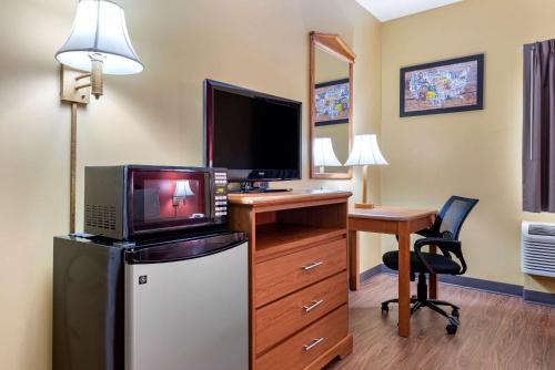a room with a desk with a tv and a refrigerator at Econo Lodge Louisville Airport in Louisville