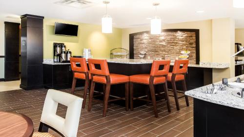 a restaurant with a bar with orange chairs at Staybridge Suites West Edmonton by IHG in Edmonton
