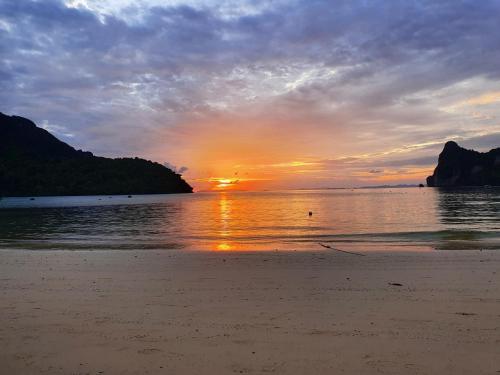 a sunset on a beach with the sun setting at Ibiza Phi Phi in Phi Phi Don
