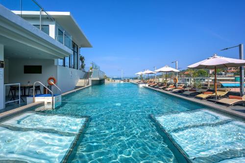 a swimming pool with chairs and umbrellas on a hotel at Zenseana Resort & Spa - Patong, Phuket in Patong Beach