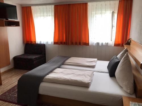 a bedroom with a bed and a chair and windows at Ferienanlage Seehof in Krumpendorf am Wörthersee