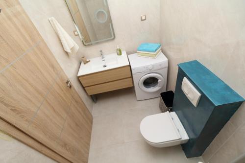 a bathroom with a toilet and a sink and a washing machine at Apartmani kike in Makarska