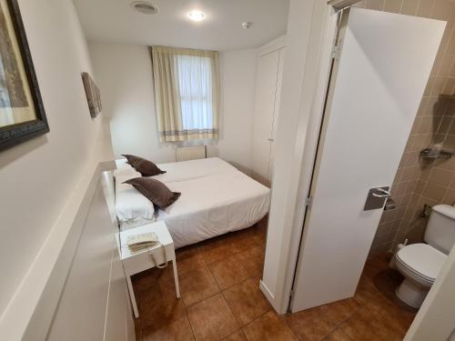 Habitación blanca pequeña con cama y aseo en Hotel Jacobeo, en Burgos