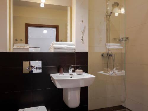 a bathroom with a sink and a shower with a mirror at VacationClub – Platan 4B Apartament 2 in Świnoujście