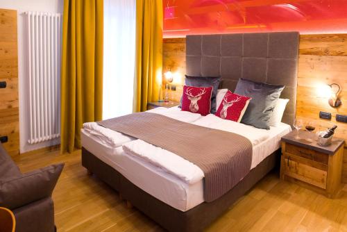 a bedroom with a large bed with red pillows at Hotel il Caminetto Sport in Canazei