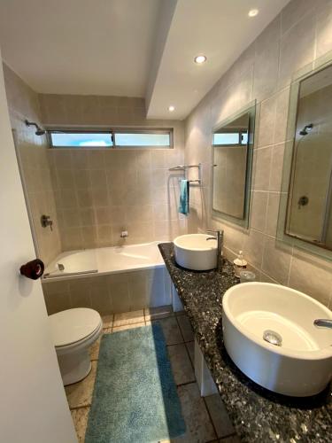 a bathroom with a sink and a tub and a toilet at Kyalanga Beachfront Apartment in Durban