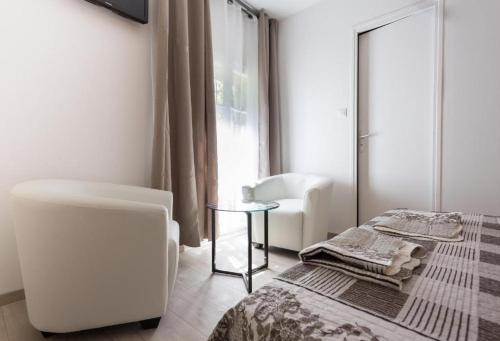 ein Schlafzimmer mit einem Bett, einem Tisch und einem Stuhl in der Unterkunft Hotel Alizéa in Avignon