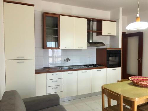 a kitchen with white cabinets and a wooden table at Residenza Iris vista mare in Gallipoli