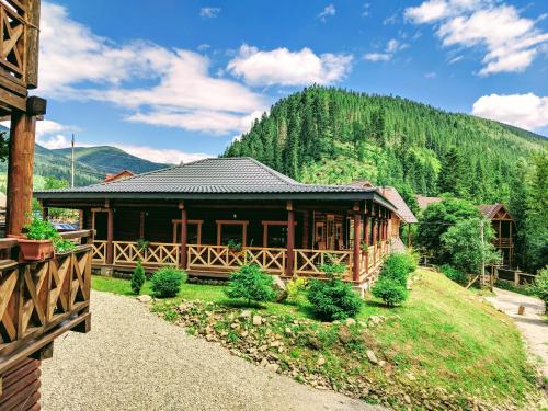 una grande cabina in legno con una montagna sullo sfondo di Asher a Tatariv