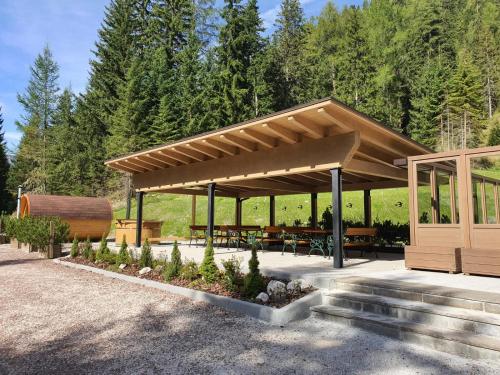 a pavilion with tables and benches in front of a forest at Hotel Villetta Maria Cottage in Canazei