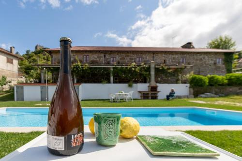a bottle of wine sitting on a table near a pool at Casa do Castelo em Arnóia in Celorico de Basto