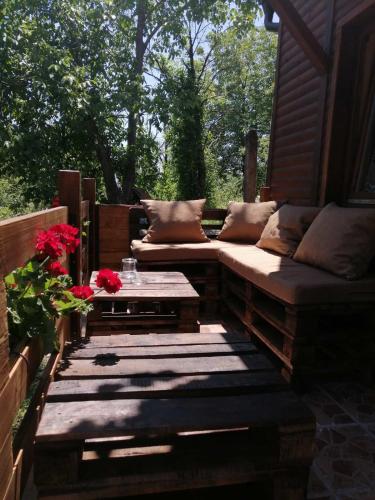 a patio with two couches and a table and flowers at Brvnara Fruska Koliba in Vrdnik