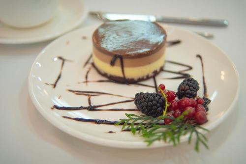 a piece of cake on a white plate with berries at Aqua Batumi Hotel & Apartments in Batumi