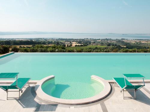 a large swimming pool with two chairs and a table at Apartment Pomele-1 by Interhome in San Lorenzo Nuovo