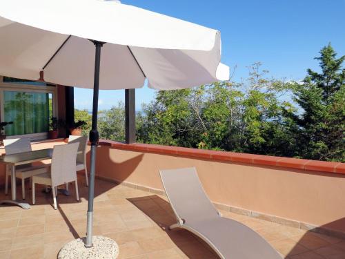 a patio with a table and a white umbrella at Apartment Il Seccione-1 by Interhome in Portoferraio