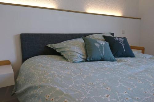 Una cama con sábanas azules y almohadas. en Gîte de charme en Ardèche : vue panoramique, plage privée en Saint-Fortunat-sur-Eyrieux