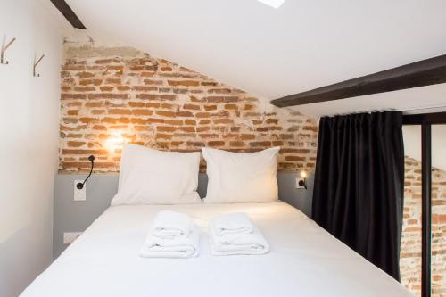 un lit dans une chambre avec un mur de briques dans l'établissement LE DIEBOLD - Appartement 2 chambres climatisé, à Toulouse