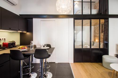 une cuisine avec des armoires noires, une table et des chaises dans l'établissement LE DIEBOLD - Appartement 2 chambres climatisé, à Toulouse