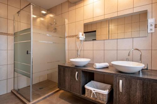 ハイドゥソボスローにあるGarden Lux Apartmanのバスルーム(洗面台2台、ガラス張りのシャワー付)