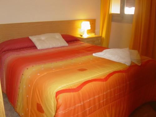 - une chambre dotée d'un lit avec une couverture orange et jaune dans l'établissement Hostal Emilio Barajas, à Madrid