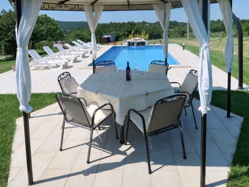 a table and chairs under a gazebo with a pool at Holiday Home Andrea - LBN415 by Interhome in Labin