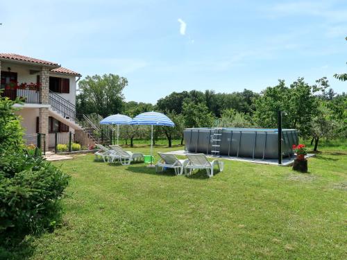 ein Hof mit Stühlen und Sonnenschirmen neben einem Haus in der Unterkunft Holiday Home Fortica by Interhome in Nedeščina