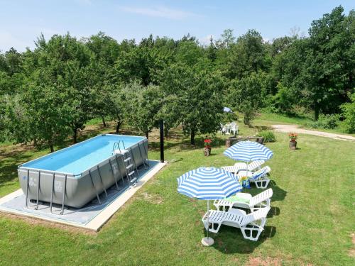 eine Gruppe von Stühlen und Sonnenschirmen neben einem Swimmingpool in der Unterkunft Holiday Home Fortica by Interhome in Nedeščina