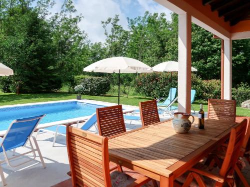 a wooden table and chairs next to a swimming pool at Apartment Ornela - LBN321 by Interhome in Nedeščina