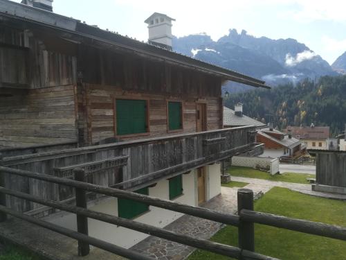 a wooden building with green windows and a mountain at App. Frassino in Sappada