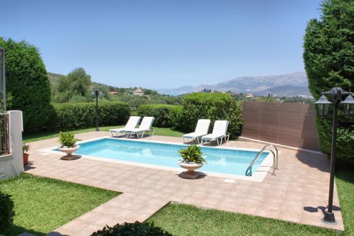 einen Pool in einem Garten mit zwei Liegestühlen in der Unterkunft Traditional Villa Mandola in Kefalonia