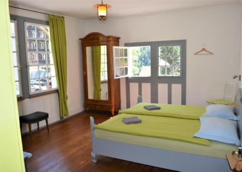 a bedroom with a green bed and two windows at Gotthard Backpacker in Wassen
