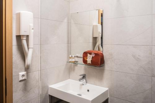 a bathroom with a sink and a red bag on the wall at Robbesscheier in Munshausen