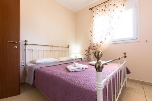 a bedroom with a bed with purple sheets and a window at Vasso Apartments 3 in Kissamos