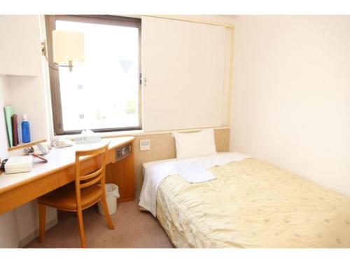 1 dormitorio con escritorio, 1 cama, escritorio y ventana en Mizusawa Ground Hotel - Vacation STAY 84945, en Oshu