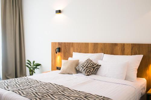 a bedroom with a white bed with a wooden headboard at Roko Garni Hotel in Brezovica