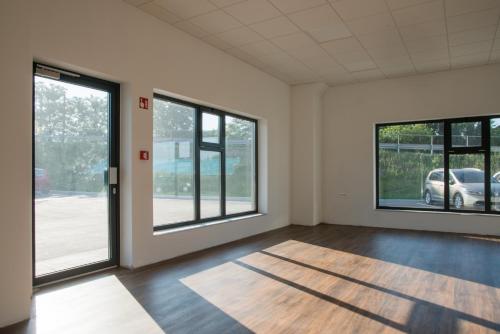 ein leeres Zimmer mit großen Fenstern und Holzböden in der Unterkunft Roko Garni Hotel in Brezovica