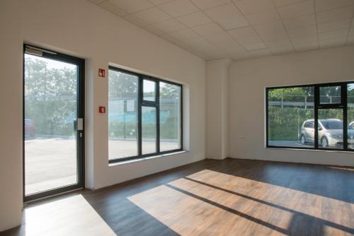 an empty room with large windows and wooden floors at Roko Garni Hotel in Brezovica