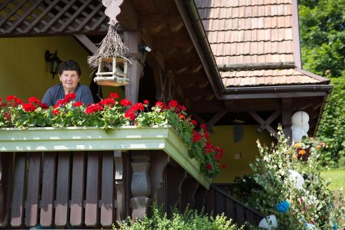 a woman standing on a balcony with red flowers at Śmietanówka Agroturystyka in Krzczonów